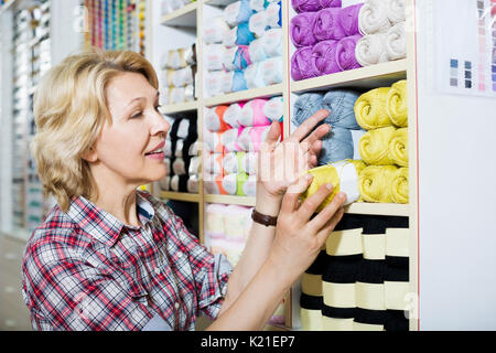 Gerne reife Frau auswählen bunte Garne im Nähen store Stockfoto