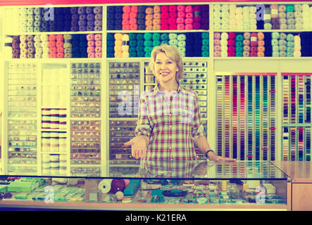 Portrait von Reifen glücklich russische frau Kassierer an der Kasse in der Stickerei Shop Stockfoto