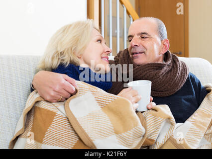 Portrait von lächelnden gefroren Rentner sitzen auf dem Sofa und Tassen Holding Stockfoto