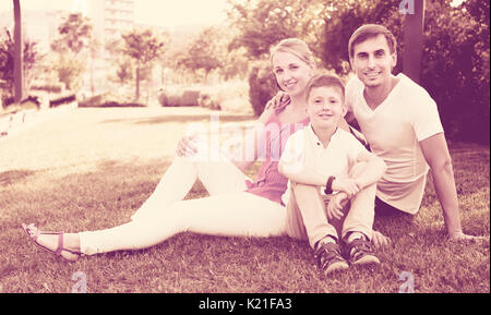 Portrait von positiven Familie mit Jungen in der Schule auf grünen Rasen in Park Stockfoto