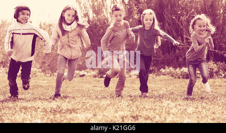 Aufgeregt Kinder voller Energie im Rennen durch das Feld ausführen Stockfoto