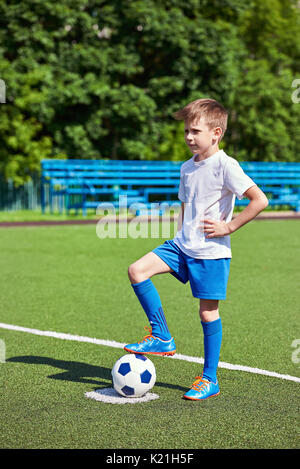 Fuß eines Fußball-Spieler in einem Fußballschuh, der auf einer Kugel auf einer künstlichen grünen Rasen des Stadions Stockfoto