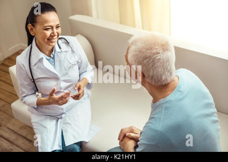 Positiv freundlich Krankenschwester sitzen auf dem Sofa Stockfoto
