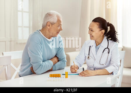 Freundliche Arzt sitzen gemeinsam mit ihren Patienten begeistert Stockfoto