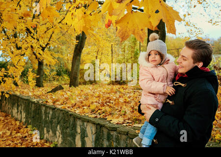 Ein Vater geht mit einem Kind Tochter im Park im Herbst. Stockfoto