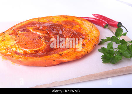 Rohes Schweinefleisch Schinken mit Gewürzen, Petersilie und Chili bereit für BBQ grillen auf weißem Hintergrund. Stockfoto