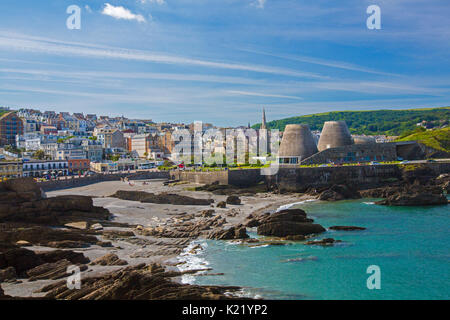 Weitläufige Stadt durch geschützten Strand gesäumt, und blauen Wasser des Ozeans an der felsigen Küste Läppen unter blauem Himmel in Ilfracombe, Devon, England Stockfoto