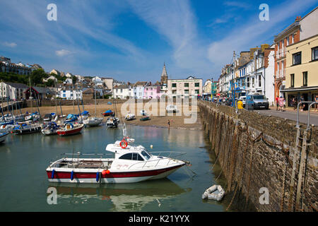 Strand und Boote im Hafen neben der schmalen Straße durch die Stadt mit bunten Gebäude unter blauem Himmel in Ilfracombe, Devon, England Stockfoto