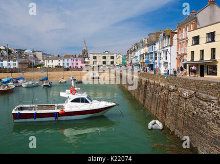 Strand und Boote im Hafen neben der schmalen Straße durch die Stadt mit bunten Gebäude unter blauem Himmel in Ilfracombe, Devon, England Stockfoto