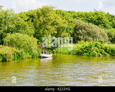 Wroxham, Norfolk, England - 21. August 2017: Drei Männer angeln am Fluss Bure aus einem kleinen Boot im Schilf am Fluss günstig Stockfoto