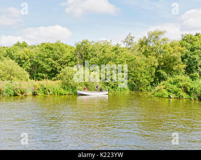 Wroxham, Norfolk, England - 21. August 2017: Drei Männer in einem kleinen Boot mit Aussenbordmotor, im Schilf an der Seite von Th ist Stockfoto