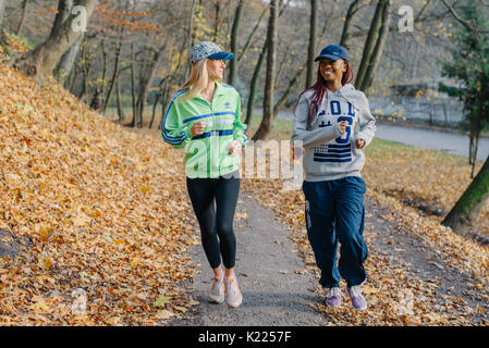 Zwei attraktive Frau im Park. Blond und afrikanischen Mädchen joggen. Golden autamn Stockfoto