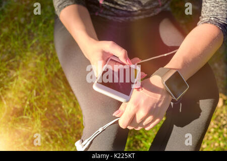 Weiblichen Athleten mit Fitness App auf Ihr smart watch Training, um die Leistung zu überwachen. Lifestyle tragbare Technologie Konzept mit Lens Flare. Stockfoto