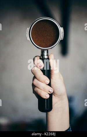 Die menschliche Hand mit einem portafilter mit frisch gemahlenem Kaffee am Morgen Stockfoto
