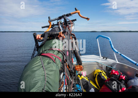 Taipalsaari, Finnland - Juli 2, 2015: Zwei Tourenräder sicher mit einem Fischerboot mit bunten Packtaschen auf dem Boot, gebunden durch den Saimaa-see, Fi Stockfoto