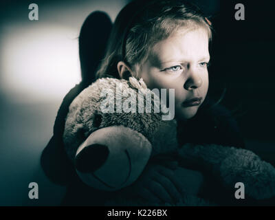 Trauriges kleines Mädchen umarmt ihren Teddy Bär - fühlt sich einsam Stockfoto