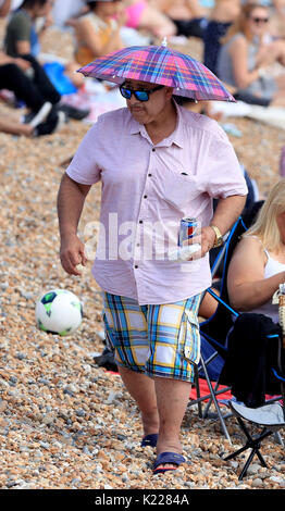 Die Menschen genießen die Bank Urlaub Sonne auf Brighton Beach in Sussex. Stockfoto