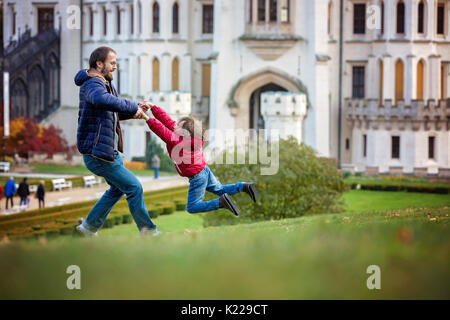 Vater, Spinning im Kreise seiner kleinen Sohn auf einer Wiese vor dem Hluboka Schloss in der Tschechischen Republik Stockfoto