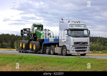 JOKIOINEN, Finnland - 25. AUGUST 2017: Silber Volvo FH 12 Transporte John Deere 1270 G Wald Feldhäcksler auf Schwanenhals Anhänger auf der Autobahn mit Rädern auf einer c Stockfoto