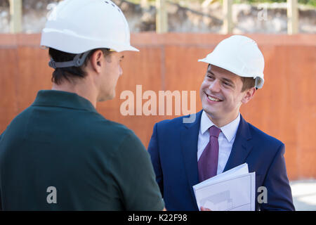 Geschäftsmann Händeschütteln mit Builder auf Baustelle Stockfoto