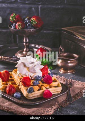 Belgische Waffeln mit Schlagsahne und frischen Beeren im Vintage Style Stockfoto