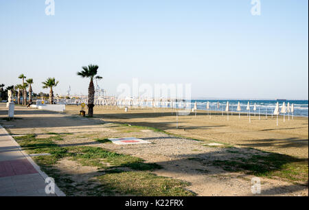 Leere Nebensaison Finikoudes Strand mit gefalteten Sonnenschirme in Larnaca, Zypern Stockfoto