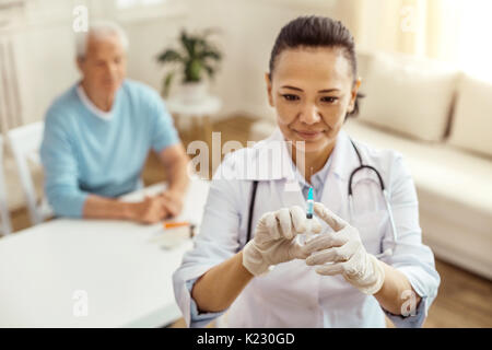 Fröhliche positive Krankenschwester Testen der Spritze Stockfoto