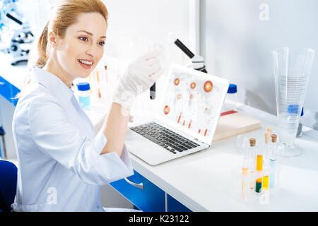 Joyful Lab Assistant Kontrolle Reagenzglas mit Reagenz Stockfoto