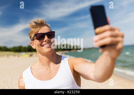 Mann mit Smartphone unter selfie auf Sommer Strand Stockfoto