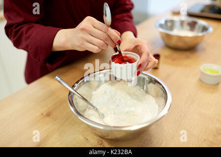 Koch Hände hinzufügen Essen Farbe in Schüssel mit Mehl Stockfoto