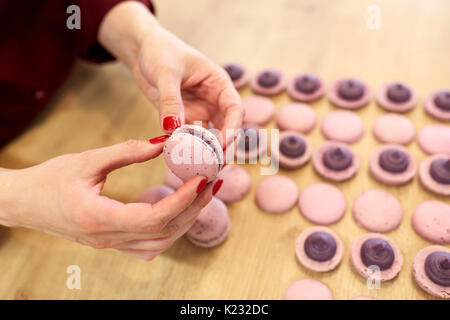 Koch sandwiching macarons Schalen mit Sahne Stockfoto