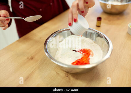 Koch Hände hinzufügen Essen Farbe in Schüssel mit Mehl Stockfoto