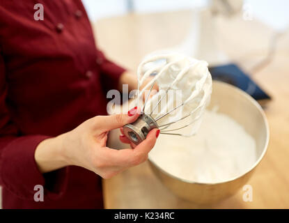 Koch mit Schneebesen und geschlagener Eischnee in Küche Stockfoto