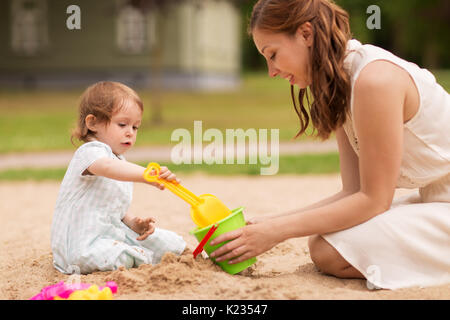 Glückliche Mutter mit Baby Mädchen spielen in Sandbox Stockfoto