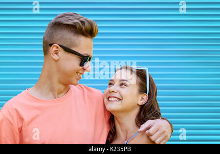 Happy teenage Paar umarmen über blauer Hintergrund Stockfoto