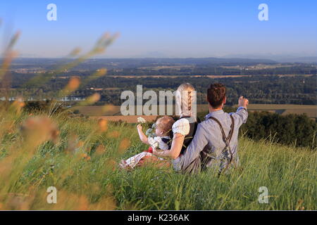 Eine Familie in Deutsch österreichischen Lederhosen Dirndel Kind sitzen Stockfoto