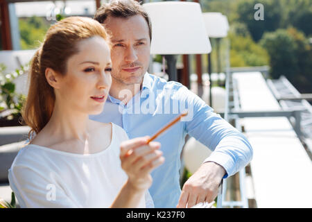 Ernsthafte netter Mann stehend hinter seinem Teamkollegen Stockfoto