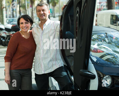 Gerne älteres Ehepaar in der Nähe von twizy Elektrische außerhalb und lächelnd Stockfoto