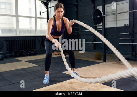 Bestimmt Frau Training mit Schlacht Seile Stockfoto