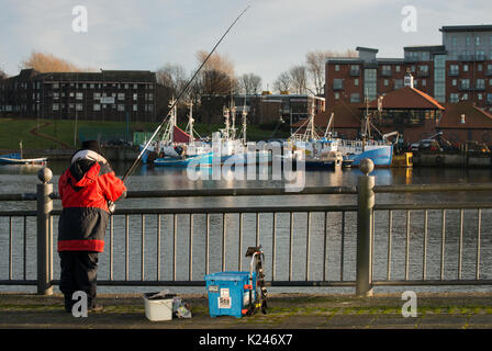 Angler mit Stab und Linie auf dem Fluss tragen bei Sunderland kleine Boote und einen Teil der Stadt im Hintergrund Stockfoto