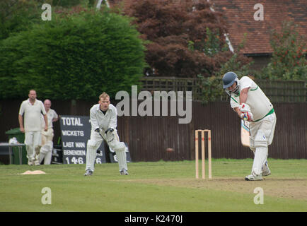 Batsman spielt einen Vorwärtsschlag in einem Cricket-Spiel im Dorf mit Wicket-Keeper in klassischer Pose und Ball deutlich zu sehen Stockfoto