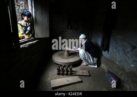 (170828) - SRINAGAR, Aug 28, 2017 (Xinhua) - ein Kaschmirischen Mädchen betrachtet ein Potter, wie er mit Schlamm traditionelle irdenen Chillum in einem Dorf im Bezirk Budgam machen, etwa 25 km südwestlich von Srinagar, Sommer Hauptstadt von Indien kontrollierten Teil Kaschmirs, Aug 28., 2017. Der Töpfer in der indischen Gemeinschaft kontrollierten Kaschmir ist verlieren ihre Lebensgrundlage durch die veränderten Lebensstile der Einheimischen, die nicht mehr Töpferwaren bevorzugen. Die Kinder der Kaschmirischen Töpfer auch sind, die nicht mit dem Beruf, wie Sie es nicht sufficing Ihre Bedürfnisse finden. (Xinhua / Javed Dar) (ZW) Stockfoto