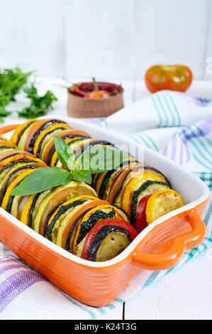 Ratatouille - Gemüse von Zucchini, Tomaten, Auberginen Scheiben in keramischen Form auf einem weißen Hintergrund. Stockfoto