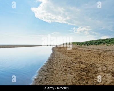 Wolken und ein dunkler blauer Himmel sind in eine Flutwelle Lagune am Strand Skegness, Lincolnshire nieder Stockfoto