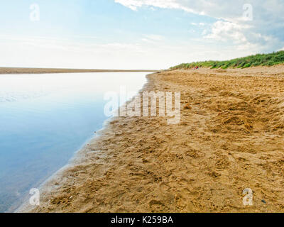 Auf Skegness Beach thse Himmel und Wolken sind in eine Flutwelle Lagune wider. menschen in der Ferne entspannen. Stockfoto