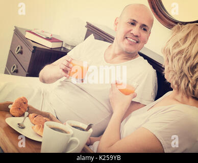 Reifer Mann und fröhlichen Freundin mit leckeren Frühstück im Bett Stockfoto