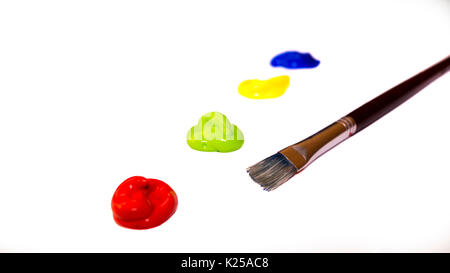 Acrylfarbe Blobs in den Farben blau, gelb, grün und rot mit einem Pinsel daneben isoliert auf weißem Hintergrund Stockfoto