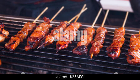 Würzig geröstete Hähnchensate/Satay-Sticks aufgereiht auf einem heißen Brennende Kohle Grill Stockfoto