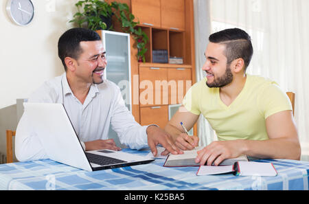 Lächelnd Professor indem private Lektion zu den glücklichen jungen Studenten zu Hause Stockfoto