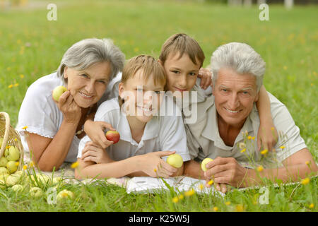 Großeltern und Enkel zusammen im Park lesen Stockfoto